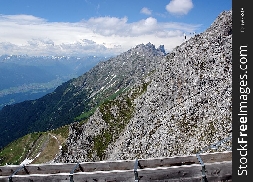 Clouds above the mountains Austrian Alpes . The snow on the rocks. Sight from the peak of Hafelkarspitze mountain .Not so far from Innsbruck . Part of the wood construction of tourist peak station . Clouds above the mountains Austrian Alpes . The snow on the rocks. Sight from the peak of Hafelkarspitze mountain .Not so far from Innsbruck . Part of the wood construction of tourist peak station .