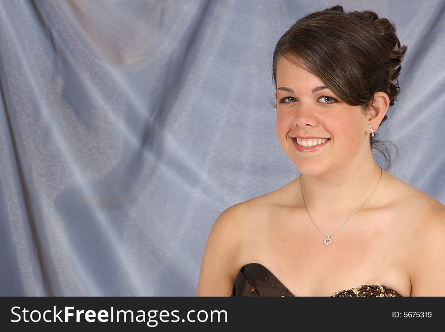 A beautiful smiling young woman with hair and makeup done.  Room for copy on left.