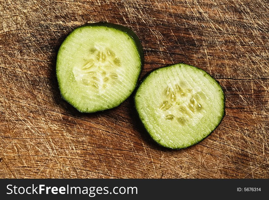 Slices of cfresh ucumber on a wooden background.