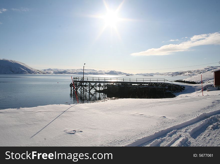 The sun in vest horisont, behind the dock. North Norwegian springtime with snow on the ground. The sun in vest horisont, behind the dock. North Norwegian springtime with snow on the ground.