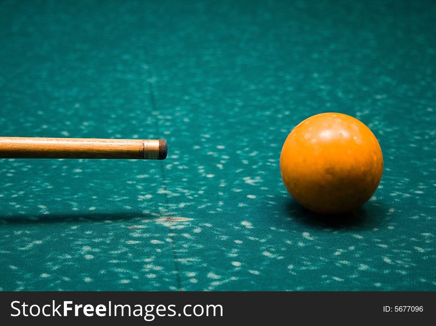 Billiard cue and yellow sphere on desk