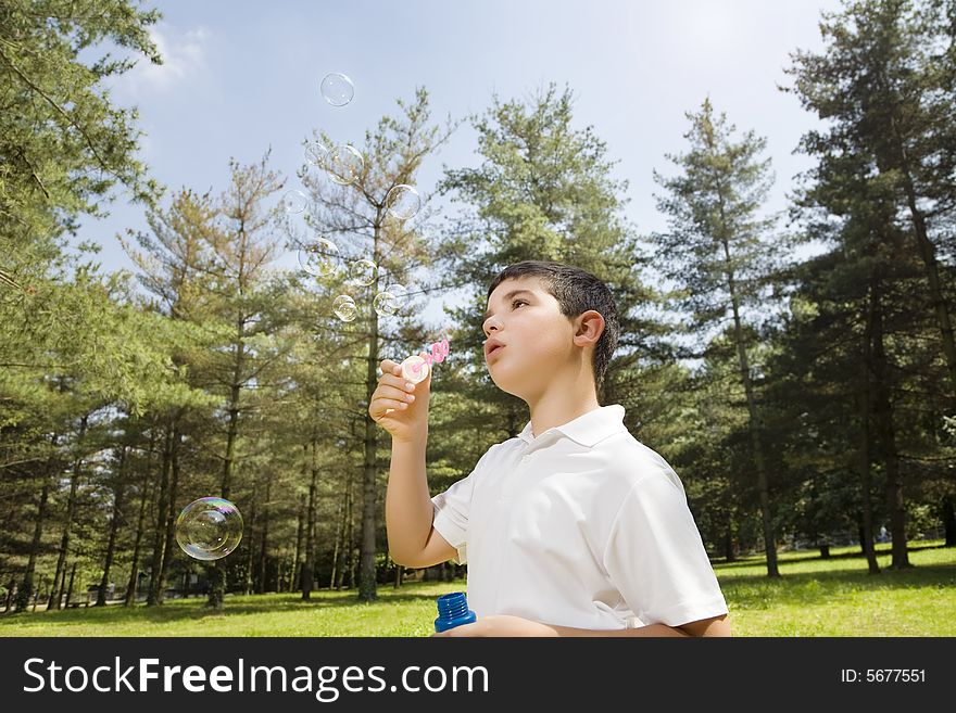 Young boy blowing bubbles in park. Copy space. Young boy blowing bubbles in park. Copy space
