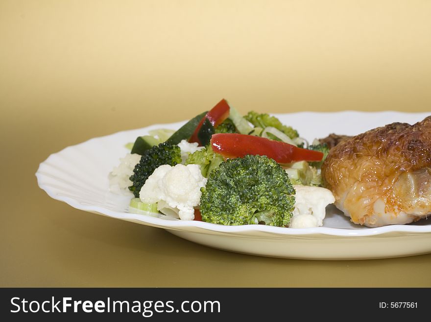 Cooked chicken with vegetables on gold background