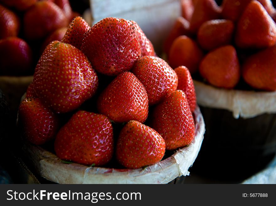 An image of small bushels filled with plump vibrant strawberries