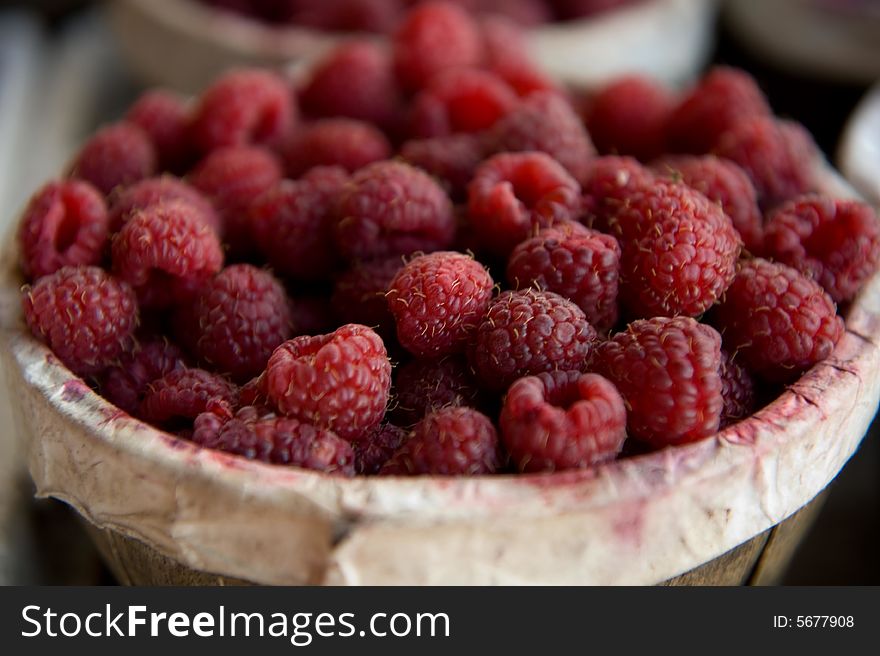 An close up image of a basket filled with ripe red raspberries