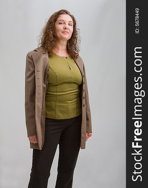 Happy business woman dressed in a green shirt, black pants and brown blazer, isolated