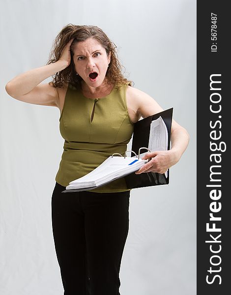 Worried business woman dressed in a green shirt and black pants holding binder, isolated