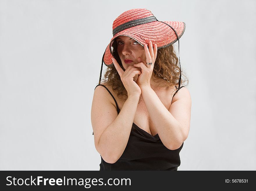 Middle aged woman wearing a red hat bending it with both hands so she can peek through, isolated. Middle aged woman wearing a red hat bending it with both hands so she can peek through, isolated