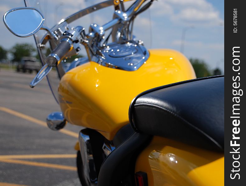 This is a rear view forward , of a yellow parked motorcycle.