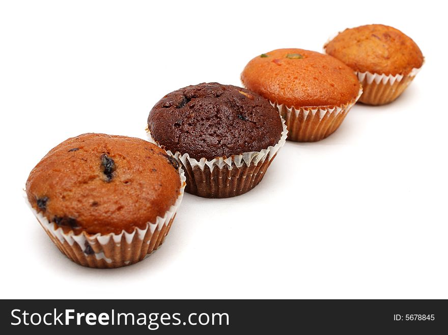 Four different flavor muffins arranged in a row on white background.