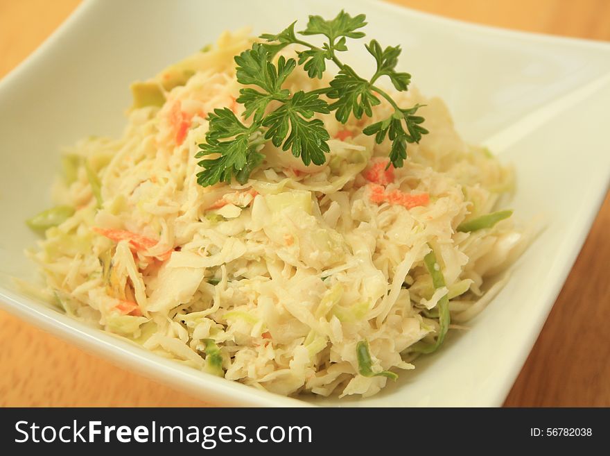 Coleslaw in small bowl on a wooden background