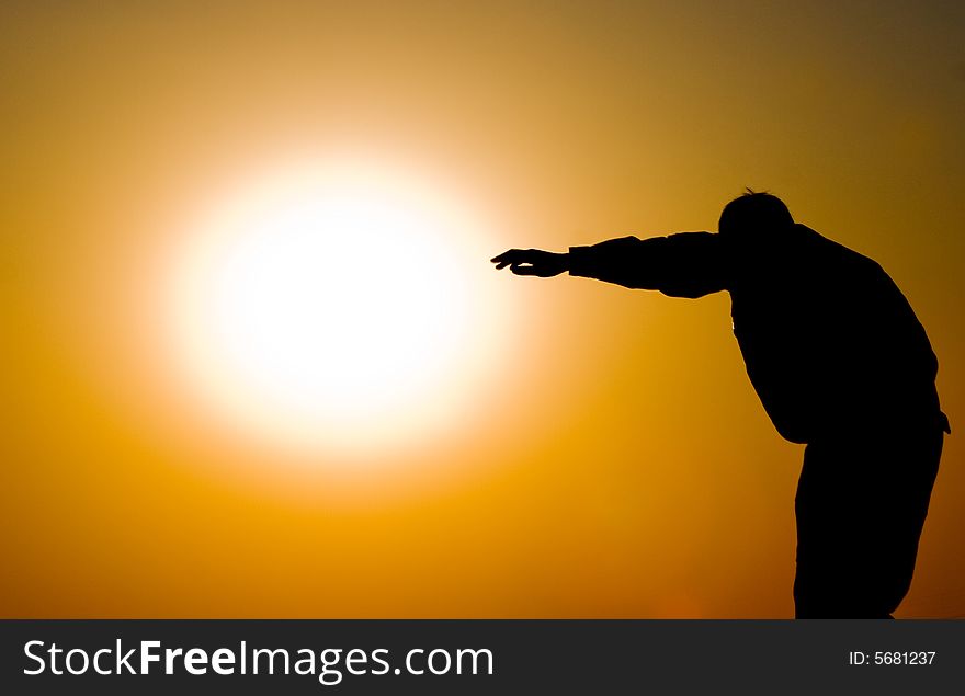 A man’s silhouette against the orangy evening sky. A man’s silhouette against the orangy evening sky.