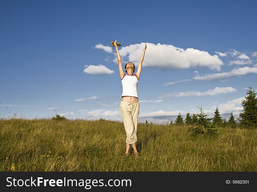 Young woman reaching to the sky in summer field. Young woman reaching to the sky in summer field