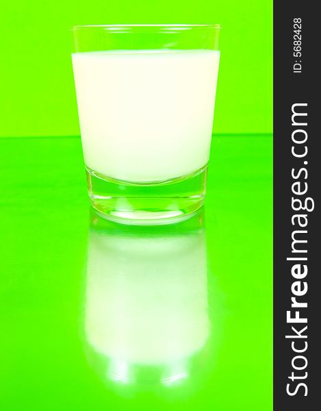 A glass of milk isolated against a green background. A glass of milk isolated against a green background