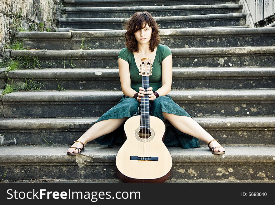 Young female guitarist on antique background. Young female guitarist on antique background