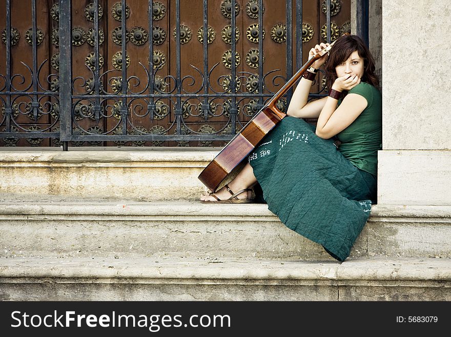 Young female guitarist begging at the church entrance. Young female guitarist begging at the church entrance