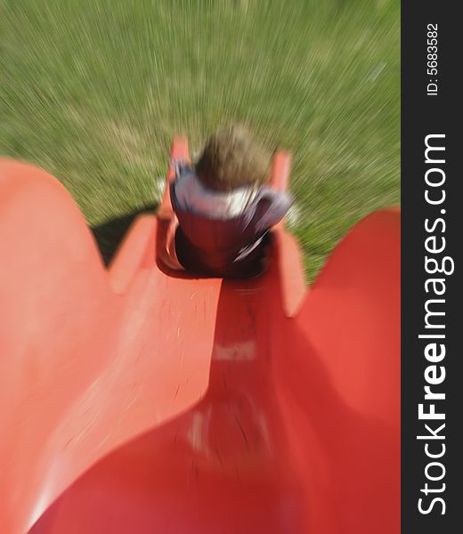 Toddler girl coming down the slide, view from above; with moving blur
