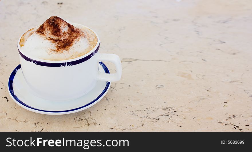 Cup of cappuccino with cacao and sugar on a marble table