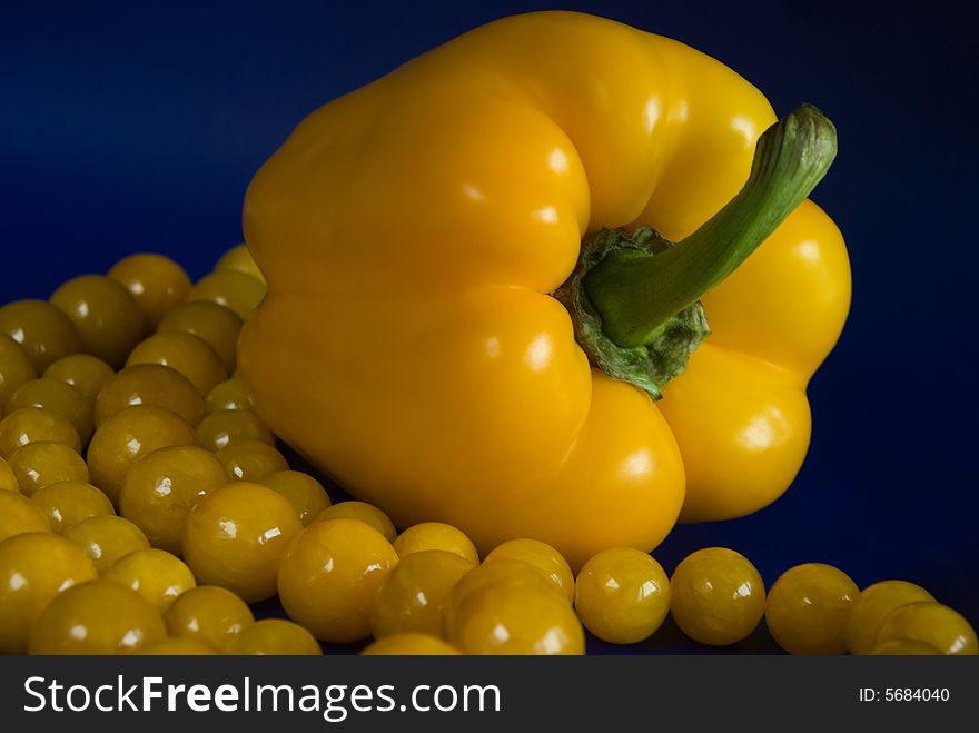 Yellow paprika and beads on blue background