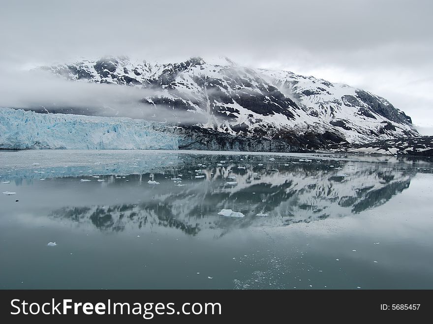 Glaciers and Mountains in Alaska reflecting off the calm waters of the bay on an overcast day. Glaciers and Mountains in Alaska reflecting off the calm waters of the bay on an overcast day.