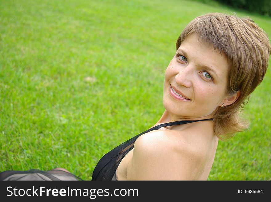 Attractive young woman against green grass. Attractive young woman against green grass