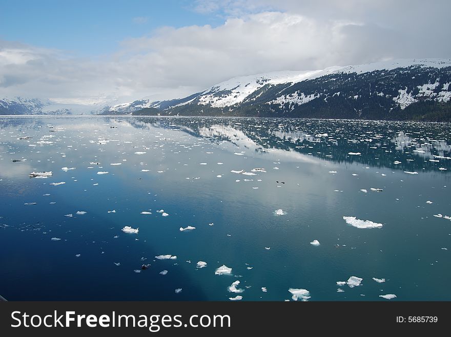 Snowy mountains in Alaska reflect off the beautiful blue bay water. Snowy mountains in Alaska reflect off the beautiful blue bay water.