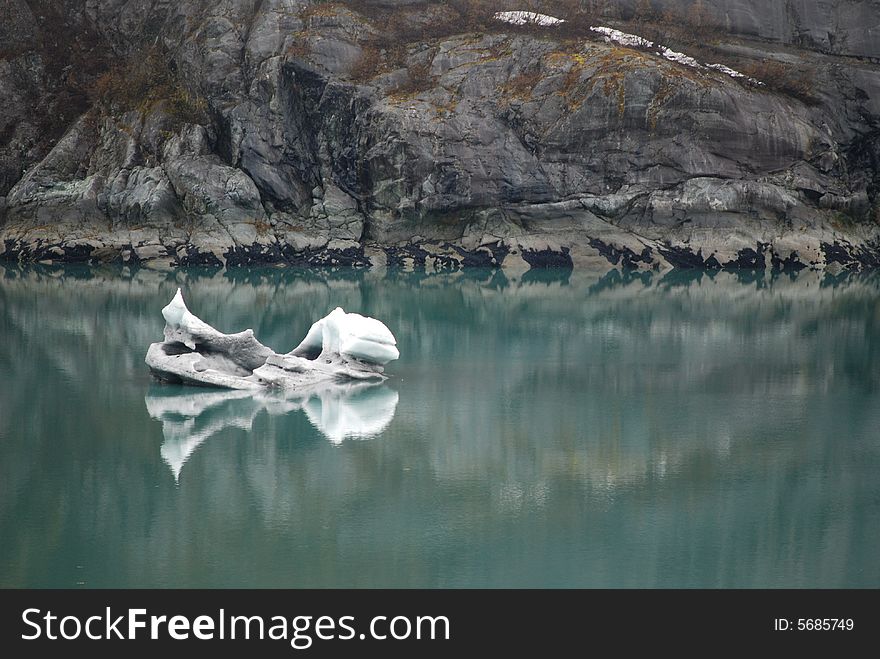 Large chunk of ice from a glacier floats by in the calm waters of an Alaskan bay. Large chunk of ice from a glacier floats by in the calm waters of an Alaskan bay.