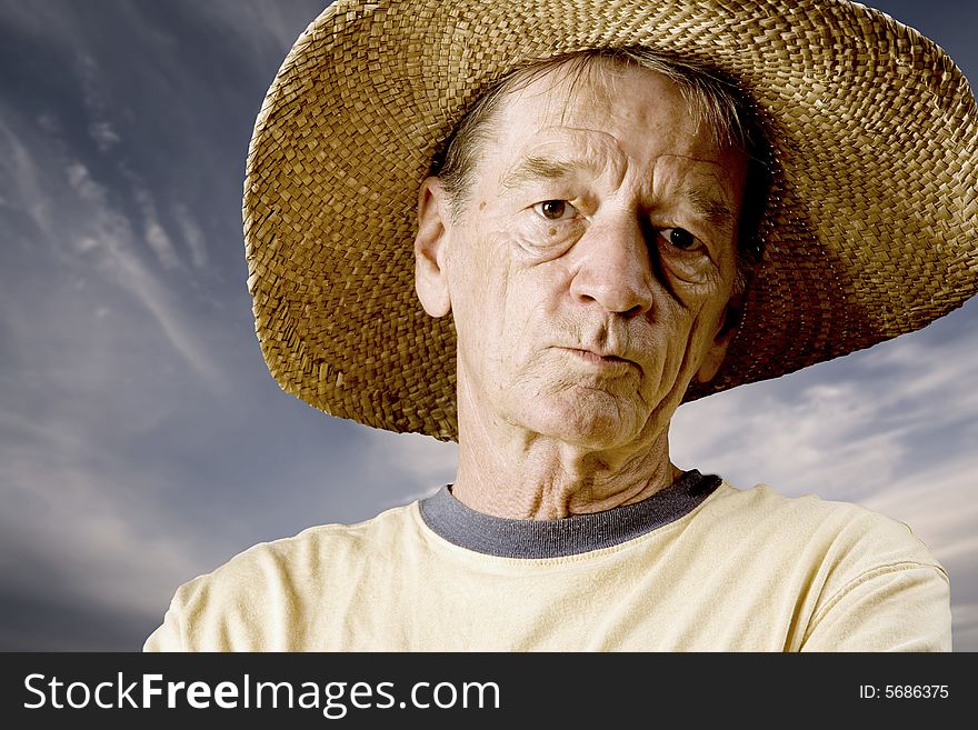 Senior in a straw hat in front of cloudy sky. Senior in a straw hat in front of cloudy sky