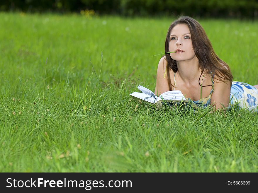 Young woman reading book in park.