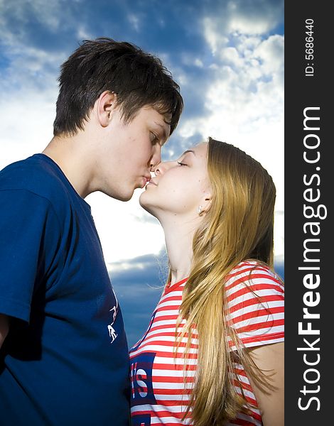 Love concept: kissing couple on a background of the blue sky