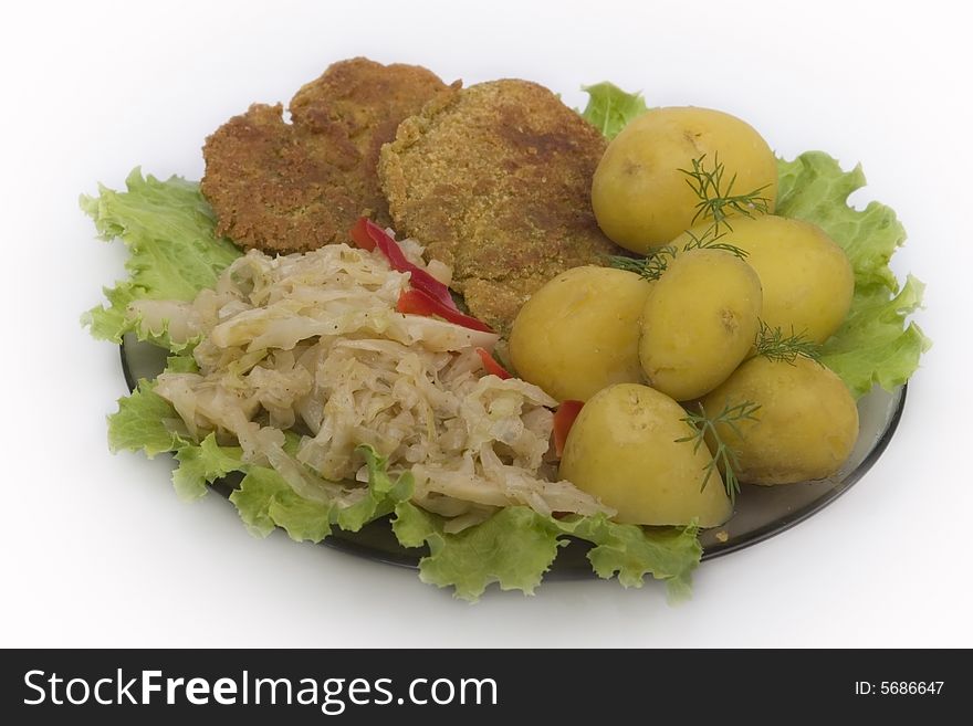 dinner composition on plate: potatoes, salad, young cabbage, pepper and pork cutlet