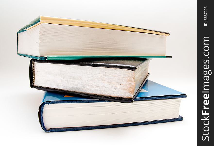 Three large textbooks stacked on top of each other. Three large textbooks stacked on top of each other.