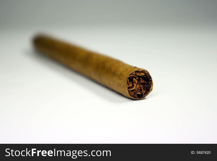 A close-up of a single cigar on a white background. A close-up of a single cigar on a white background