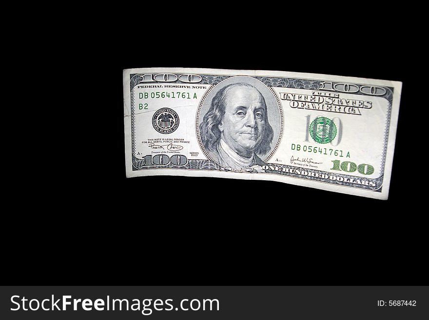 A worn-out 100 dollar banknote on a black isolated background. A worn-out 100 dollar banknote on a black isolated background