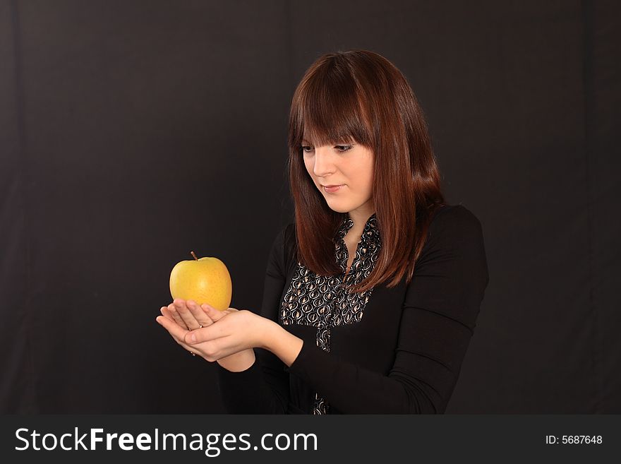 The red-haired girl holds an apple in hands. The red-haired girl holds an apple in hands