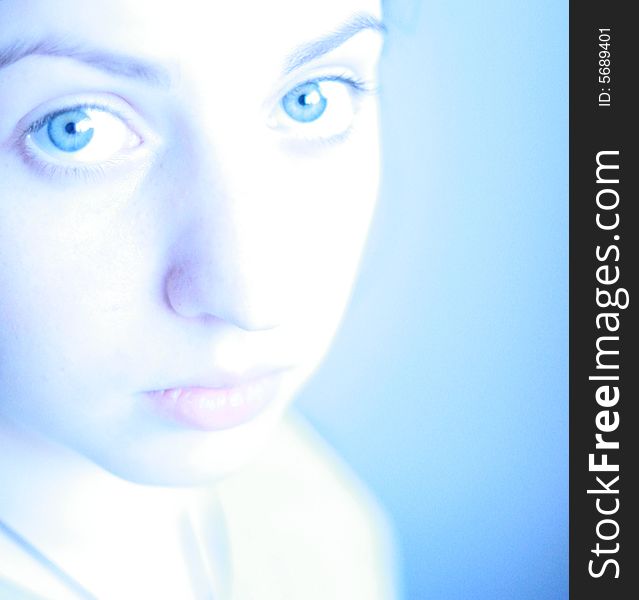The young girl with blue eyes. A blue background. The young girl with blue eyes. A blue background