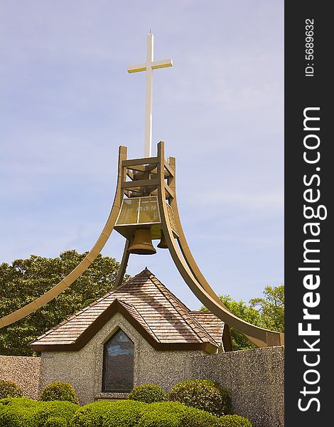 A bell tower and a cross on a display in a public park. A bell tower and a cross on a display in a public park