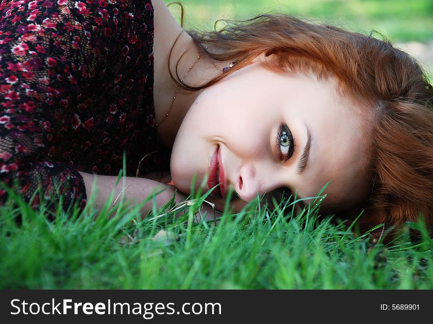 Portrait of beautiful girl, with red hairs, lying on a green grass. Portrait of beautiful girl, with red hairs, lying on a green grass