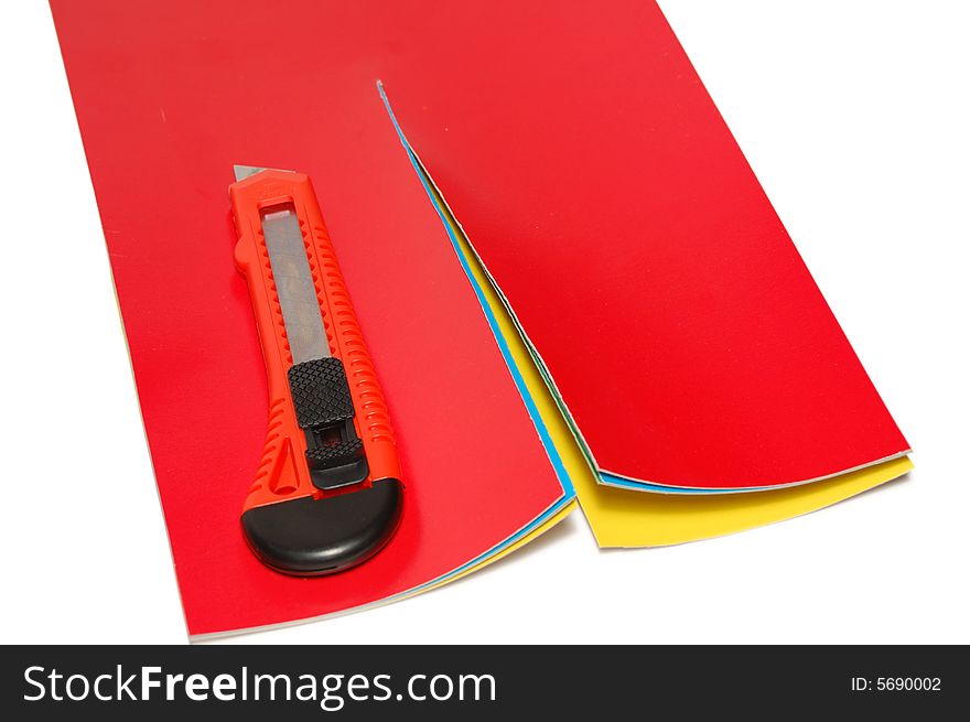 The knife cuts a color paper isolated on a white background. The knife cuts a color paper isolated on a white background