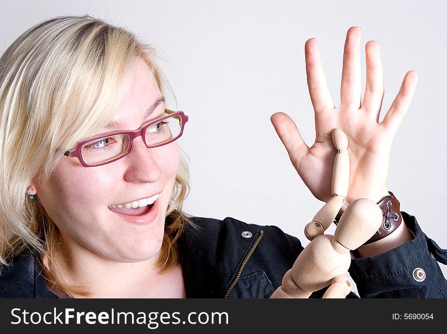 Young modern woman giving a high-five to a wooden stick man toy. She looks as if she has scored a deal or goal. Young modern woman giving a high-five to a wooden stick man toy. She looks as if she has scored a deal or goal.