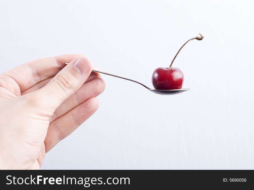Red sweet cherry on silver spoon at white background. Red sweet cherry on silver spoon at white background