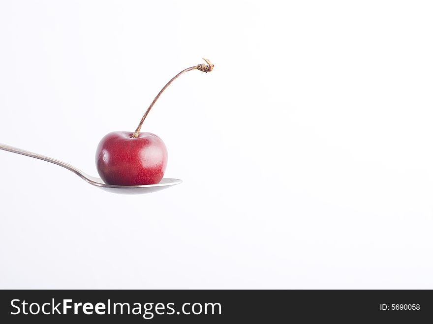 Red sweet cherry on silver spoon at white background. Red sweet cherry on silver spoon at white background