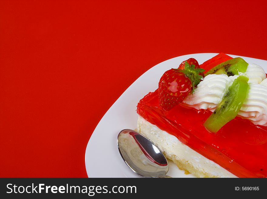 Cream and jelly cake with fruits, spoon