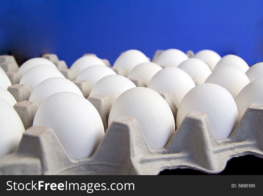 A couple of dozen eggs with blue background