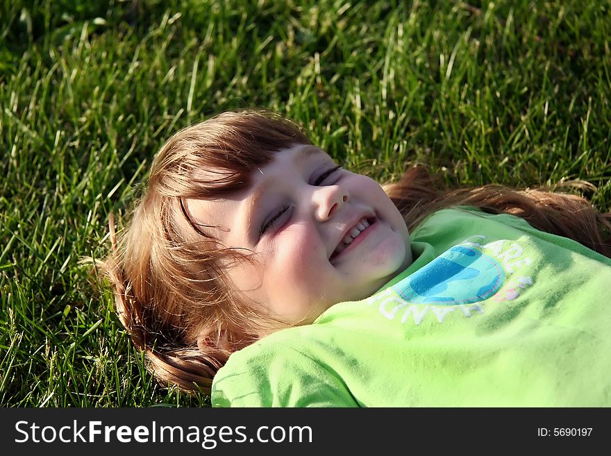 A happy little girl laying in the grass