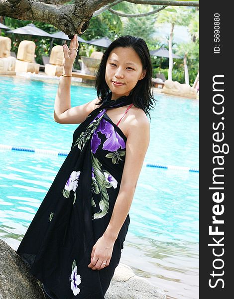 Asian woman in a pretty summer sarong by the pool. Asian woman in a pretty summer sarong by the pool.