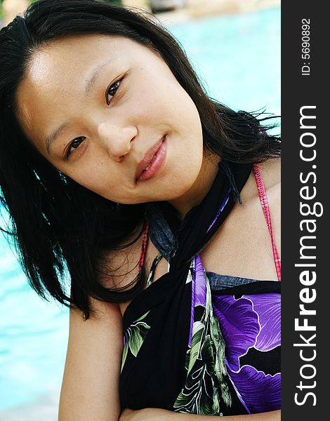 Asian woman in a pretty summer sarong by the pool. Asian woman in a pretty summer sarong by the pool.