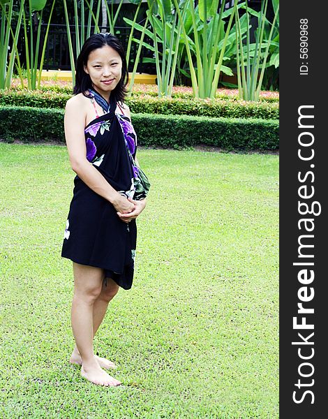 Asian woman in a pretty summer sarong in a tropical garden. Asian woman in a pretty summer sarong in a tropical garden.