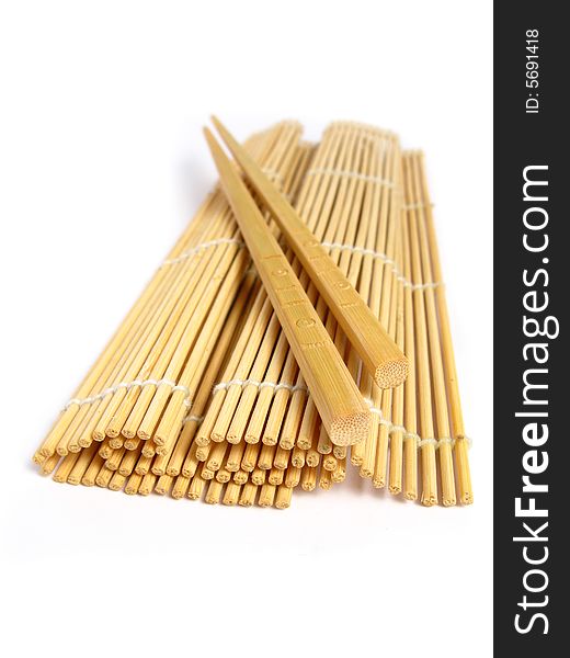Chopsticks and bamboo mat on white background