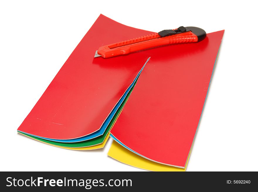 The knife cuts a color paper isolated on a white background. The knife cuts a color paper isolated on a white background